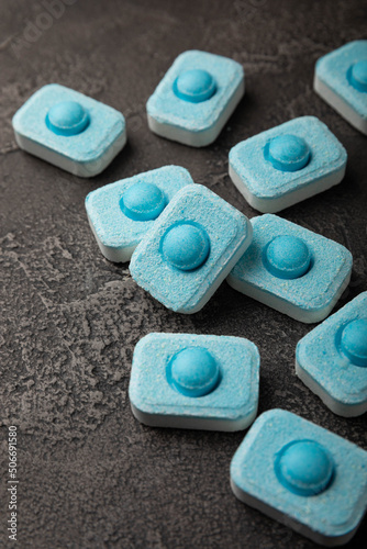 Water softener tablets on black texture background. Capsules for washing machines and dishwashers, preventing limescale. Place to copy.