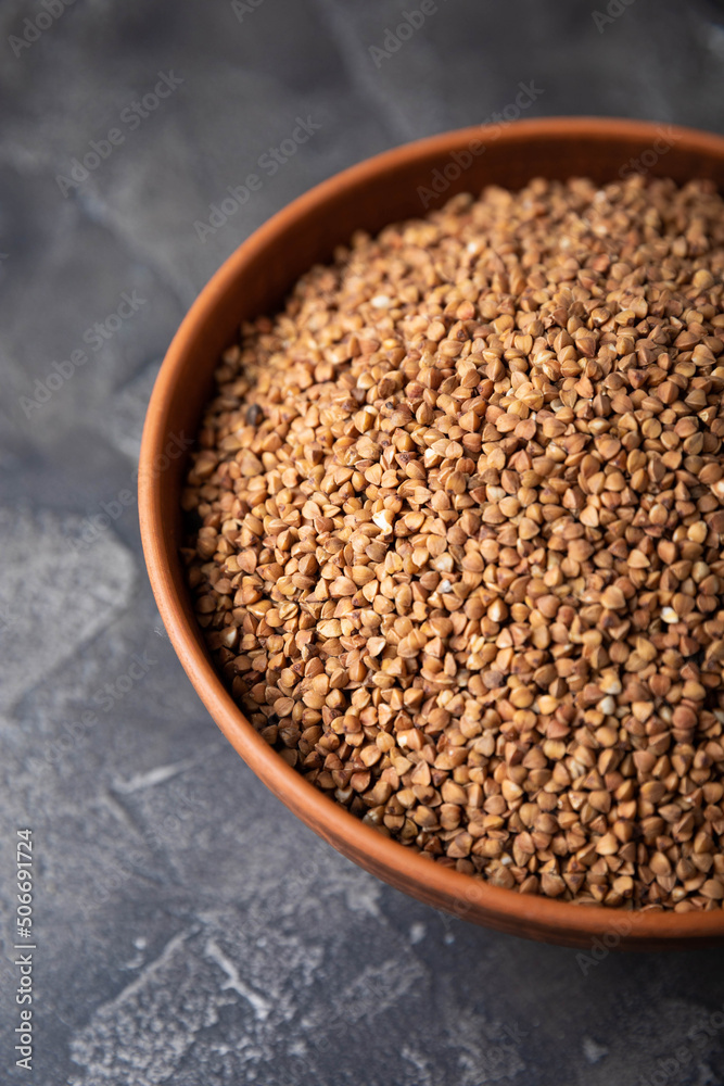 Buckwheat in a bowl on a black textured marble background. Raw buckwheat. Ingredients for gluten free cereal. Healthy food. Place to copy. Buckwheat in a bowl on a black textured marble background. Raw buckwheat. Ingredients for gluten free cereal. Healthy food. Place to copy.