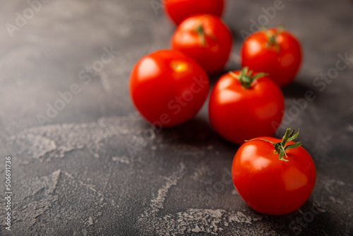 Fresh red tomatoes on black texture marble background. Cherry tomatoes with green stems. Fresh vegetables. Place to copy.organic food