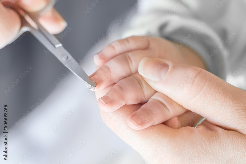 mother cuts baby's fingernails with special children's scissors. close up. manicure for newborns.