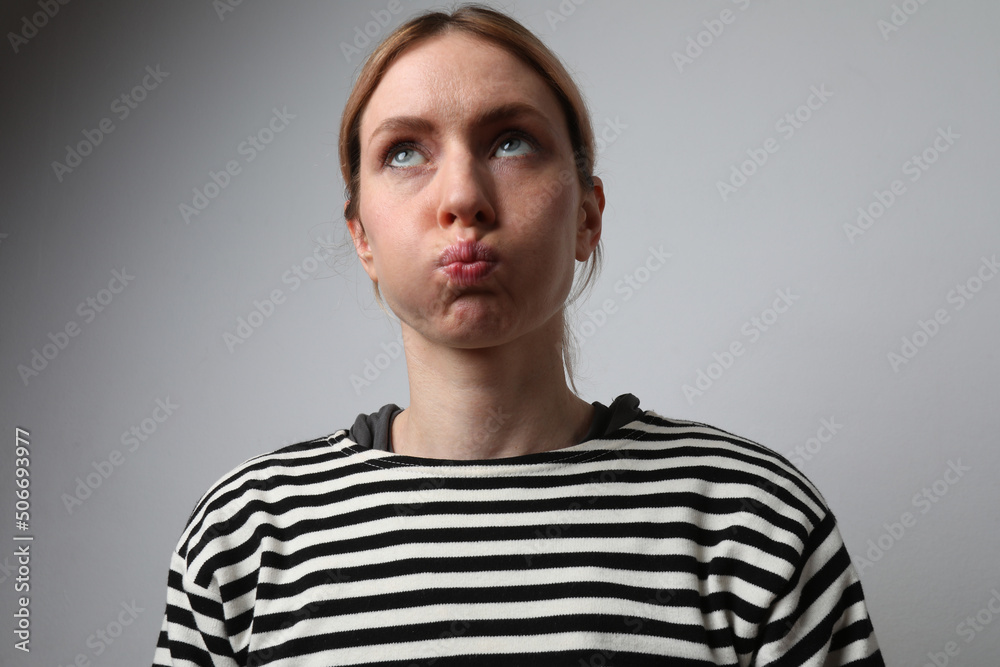 Fototapeta premium Tired and worried woman inflates cheeks and looking away. Mock-up. Isolated.
