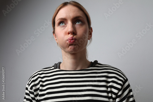 Tired and worried woman inflates cheeks and looking away. Mock-up. Isolated.