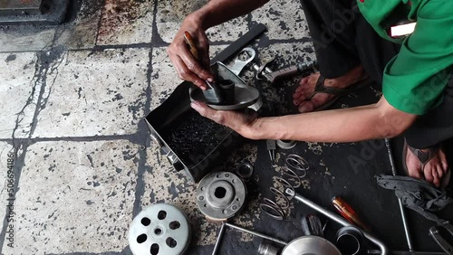 the mechanic's hand is cleaning the automatic motor CVT components manually during routine service. 