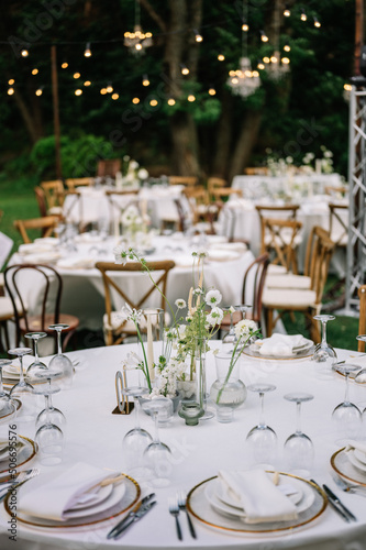magical rustic wedding tables outside in the garden with hanging light and flowers, chairs, outdoor ceremony in the open air 