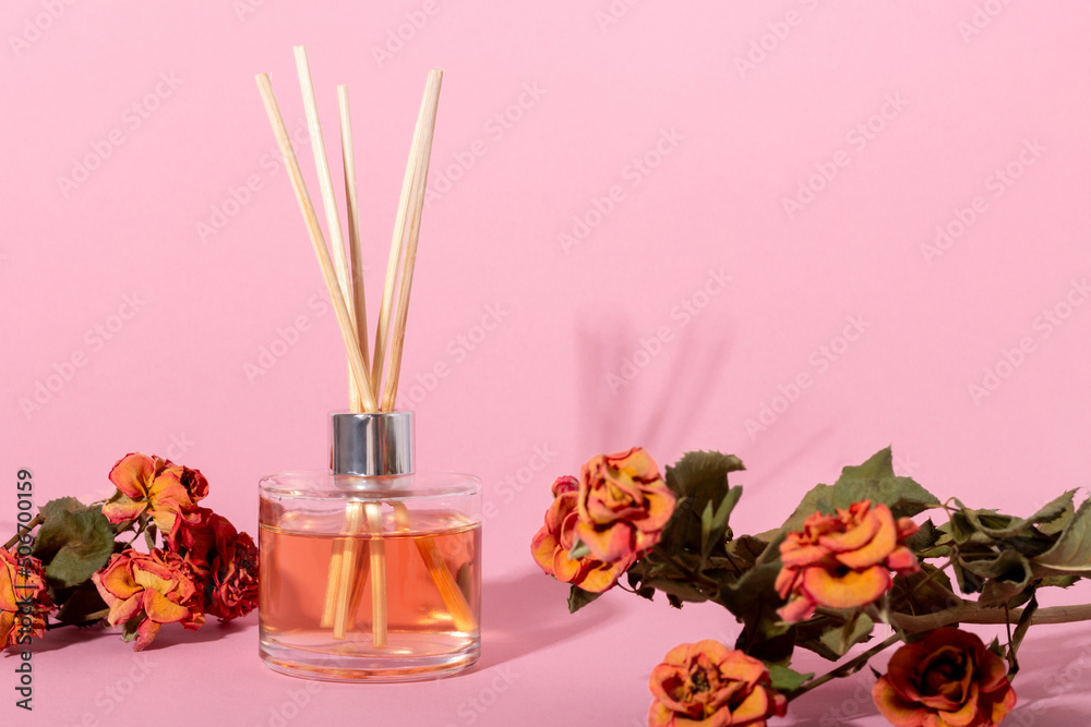 reed diffuser with flowers. Incense sticks for the home with a floral scent with hard shadows. The concept of eco-friendly fragrance for the home - obrazy, fototapety, plakaty 