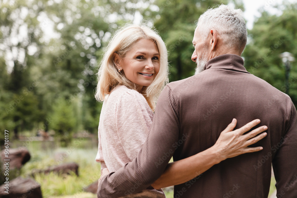 Mature happy romantic couple hugging embracing while walking in park together. Bonding, love and relationship concept