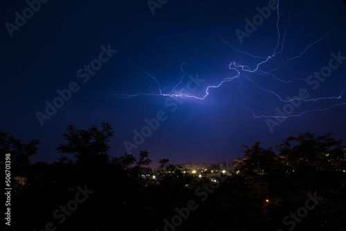 Lightning discharges over the city. A summer thunderstorm at night.