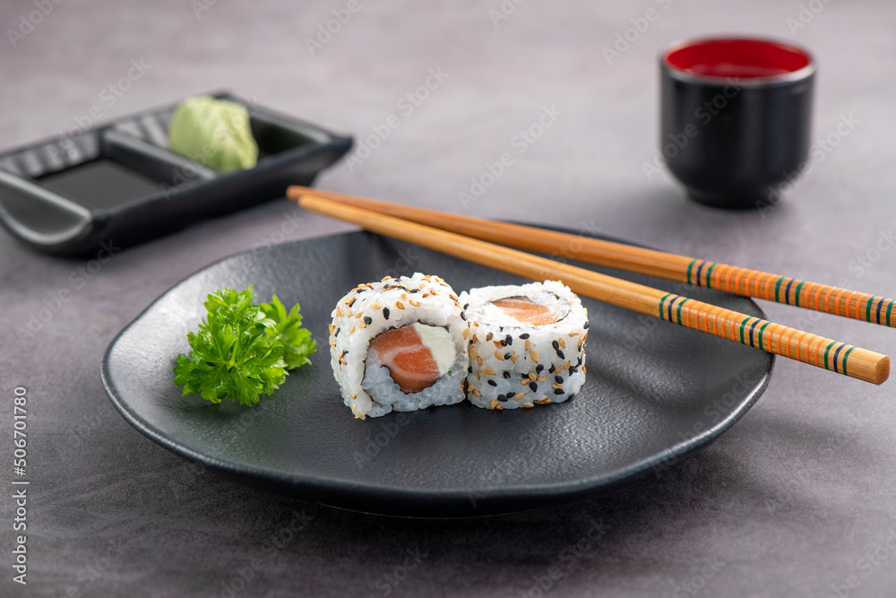 Salmon Uramaki Sushi couple on dark plate. Studio shoot on slate background. Salmon Uramaki Sushi couple on dark plate. Studio shoot on slate background.