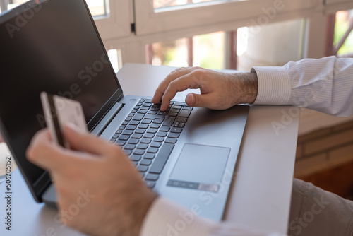 Man paying with his credit card online with the laptop.