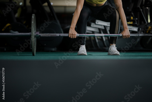 A woman is working out in a fitness center, lifting steel numbells to build muscles in her arms and shoulders. Fitness concepts for health and wellness lifestyles, build muscles of the body.