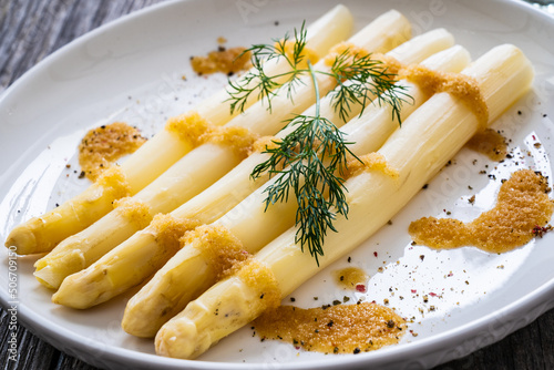 White boiled asparagus in breadcrumbs with butter served on wooden table