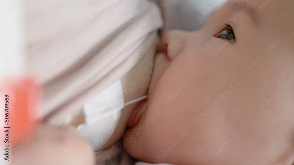 Mother breastfeeding baby with SNS system. Close up view - obrazy, fototapety, plakaty 