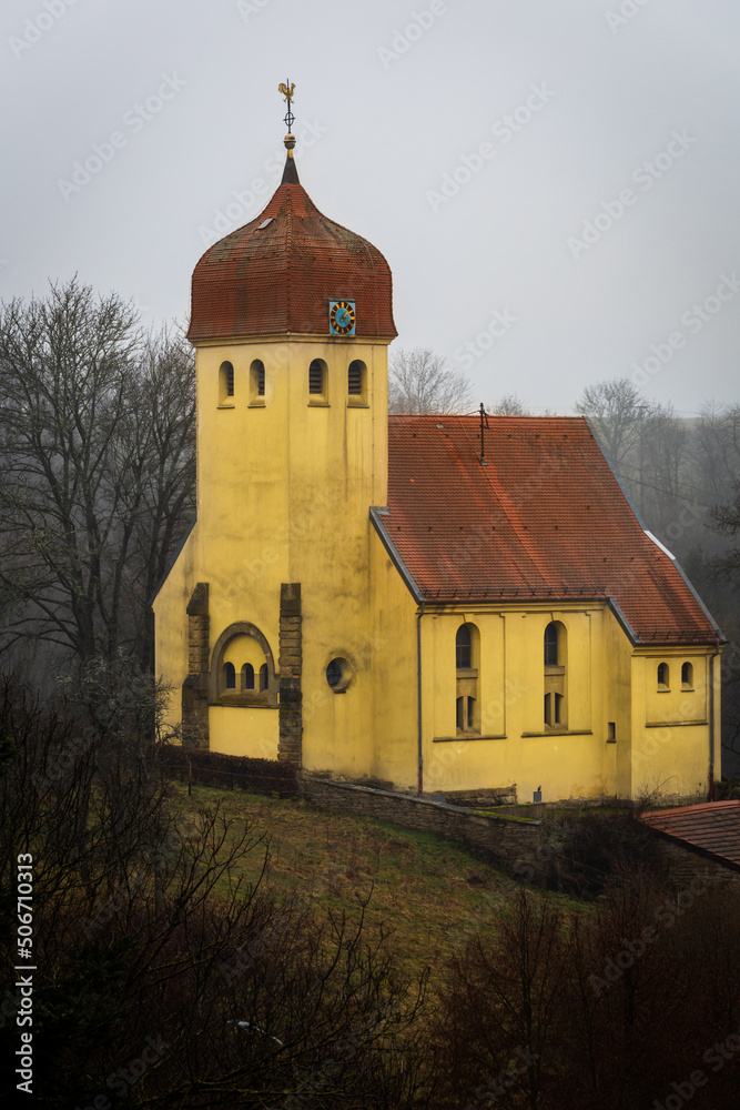 Old protestant  church in Germany sitting on a hill with dilapidated paint on a cloudy rainy day