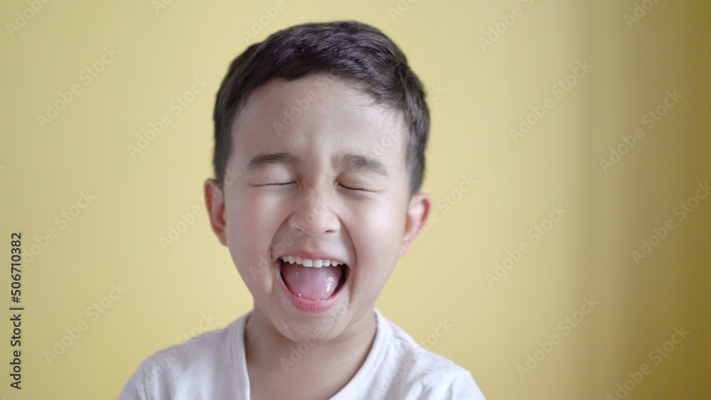 Cute boy looking at camera and grimaces on colour background Cute boy looking at camera and grimaces on colour background