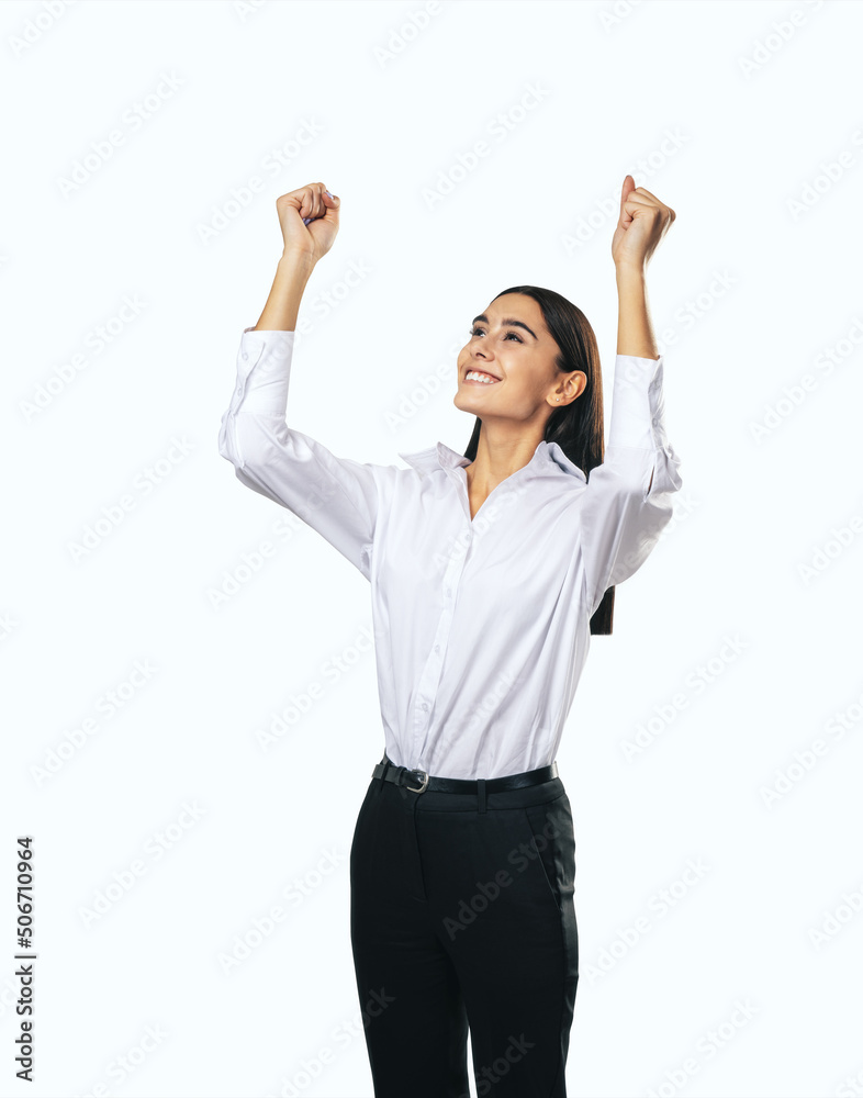 Joyful and satisfied woman in white shirt with raised hands showing her power, winner and achievement concept, isolated on white background, close up Joyful and satisfied woman in white shirt with raised hands showing her power, winner and achievement concept, isolated on white background, close up