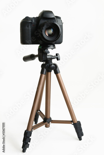 Modern compact tripod with camera on white with shadow. Front view