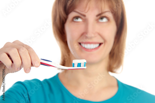 Portrait of a smiling young woman holding toothbrush with toothpaste isolated over white background