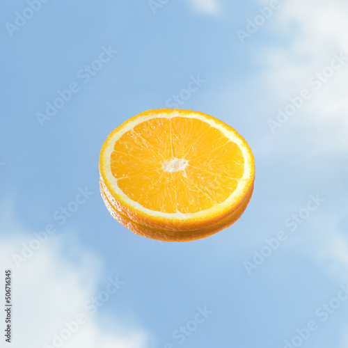 A slice of orange and a blue sky. Summer outdoor minimal fruit concept.