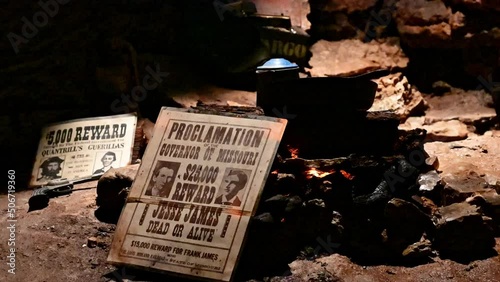 Jesse James wanted poster leans up against campfire and coffee pot in cave hideout near Ozark USA. Gang of robbers and folk heroes often hit loot in caverns until law stopped looking for them. photo