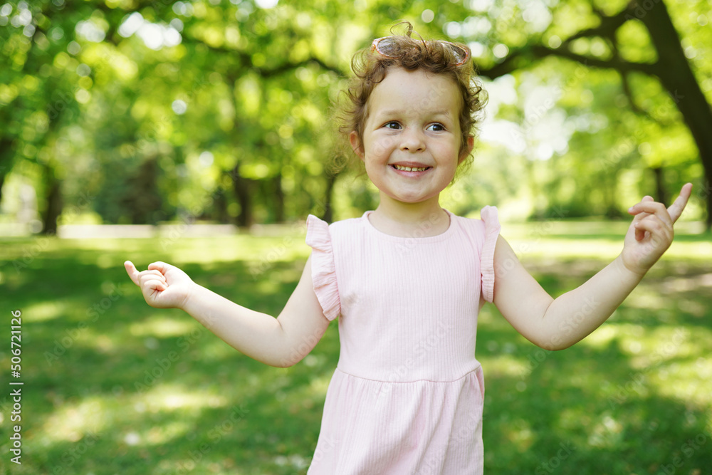 Child girl with beautiful curly hair in pink dress in amazing sunset light. Portrait of smilling kid at nature Child girl with beautiful curly hair in pink dress in amazing sunset light. Portrait of smilling kid at nature