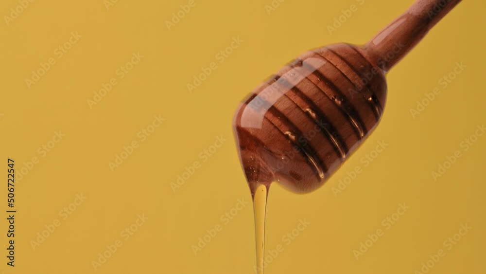 Healthy Food Concept. Delicious sweet liquid honey flows down from a wooden spoon on yellow background. Organic healthy honey, vitamins, sweet dessert. Honey dripping from a spoon Healthy Food Concept. Delicious sweet liquid honey flows down from a wooden spoon on yellow background. Organic healthy honey, vitamins, sweet dessert. Honey dripping from a spoon