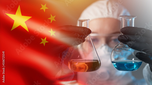Scientific research in China. Scientist compares chemical liquids in flasks against the background of PRC flag. Chinese chemist or doctor. Woman with flasks in her hands. Experiment result