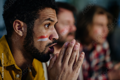 Nervous football fans friends watching German national team in live soccer match on TV at home