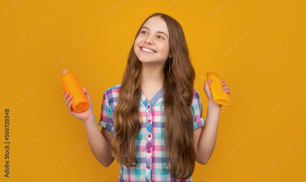 happy child with hair conditioner bottle on yellow background happy child with hair conditioner bottle on yellow background