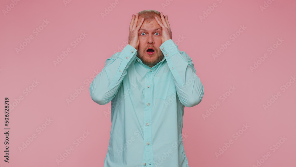 Stressed depressed adult man 30 years old in blue shirt expresses his fear and waves his hands away from danger, waving no. Scared fearful young guy isolated alone on pink studio wall background Stressed depressed adult man 30 years old in blue shirt expresses his fear and waves his hands away from danger, waving no. Scared fearful young guy isolated alone on pink studio wall background