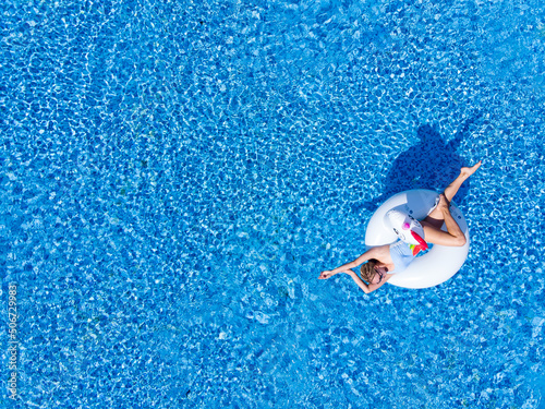 Woman on unicorn pool float in pool in hotel. Summer holidays. Aerial top view from drone © Marharyta