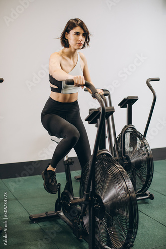 Crossfit woman doing intense cardio training on exercise air bike
