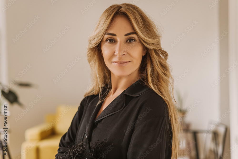 Pretty caucasian adult woman in silk pajamas looks at camera on blurred