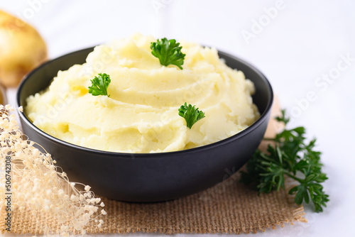 Mashed potato with pasley in black bowl on white background