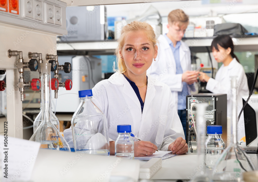 Fototapeta premium Portrait of European female scientist working with her colleagues in biochemical laboratory