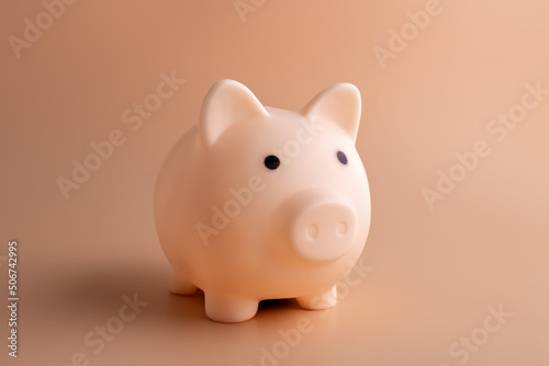 Beige piggy bank on a light brown background.