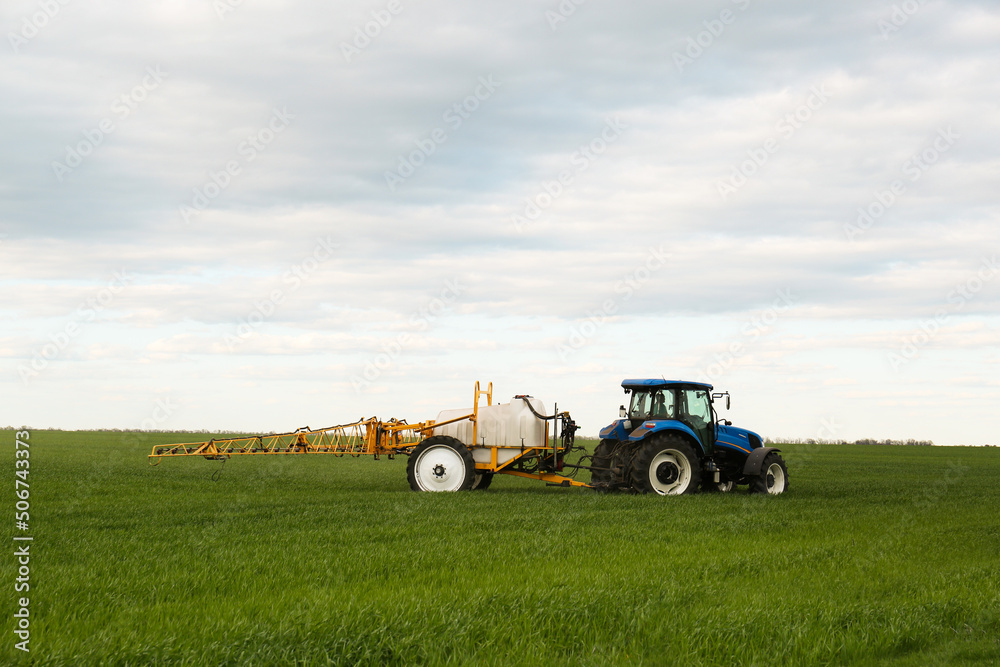 Tractor spraying pesticide in field on spring day. Agricultural industry Tractor spraying pesticide in field on spring day. Agricultural industry