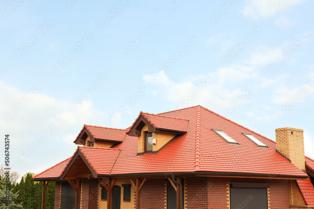Modern house with red roof against cloudy sky