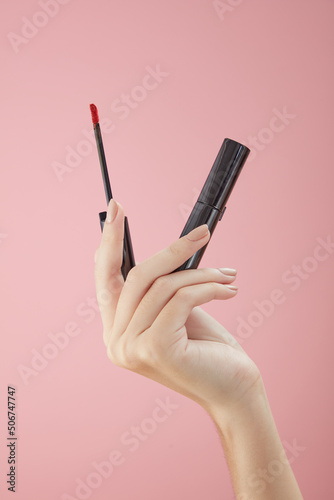 Top view of hand model holding lipstick on hand in pink background for cosmetic advertising