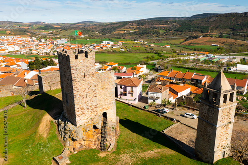 Aerial view of remains of medieval fortified stone castle in Portuguese township of Mogadouro towering above terracotta roofed residential buildings on sunny spring day photo