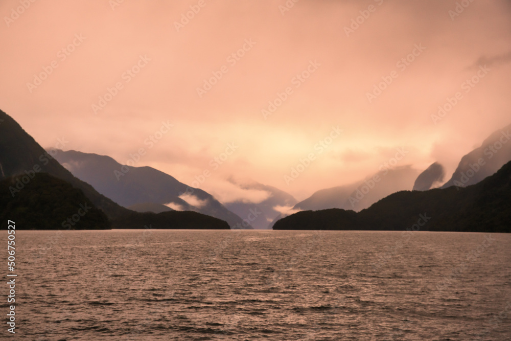 The mountains silhouetted in the murky atmosphere on a bad weather day in the fjord
