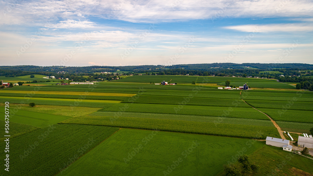 Aerial View of Farmlands With Barns and Silos, Looking Over the Hills and Fields of Rich Crops Growing on a Sunny Summer Day