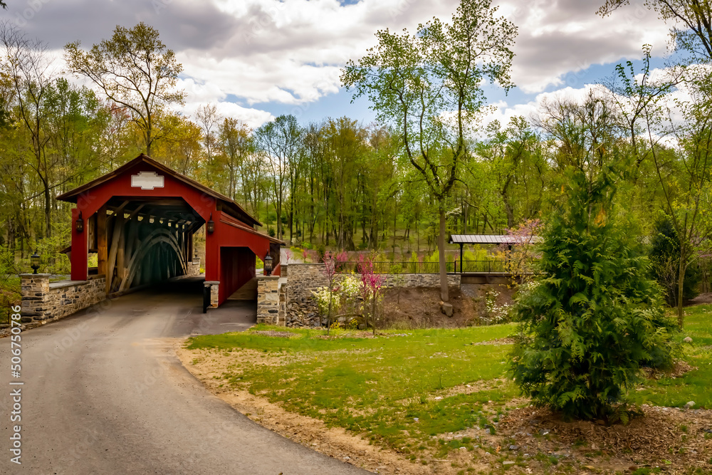 View of a Restored Burr Truss Covered Bridge on a Country Road With Stone Approach Walls on a Mostly Sunny Day