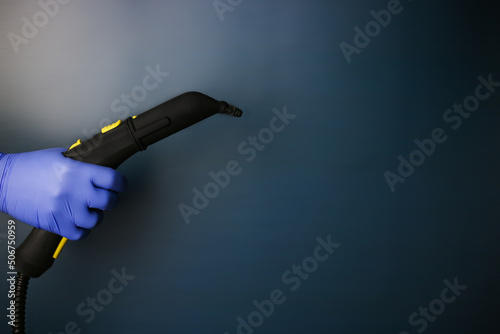 Steam cleaner in hand with hot steam on an isolated dark background. Professional cleaning