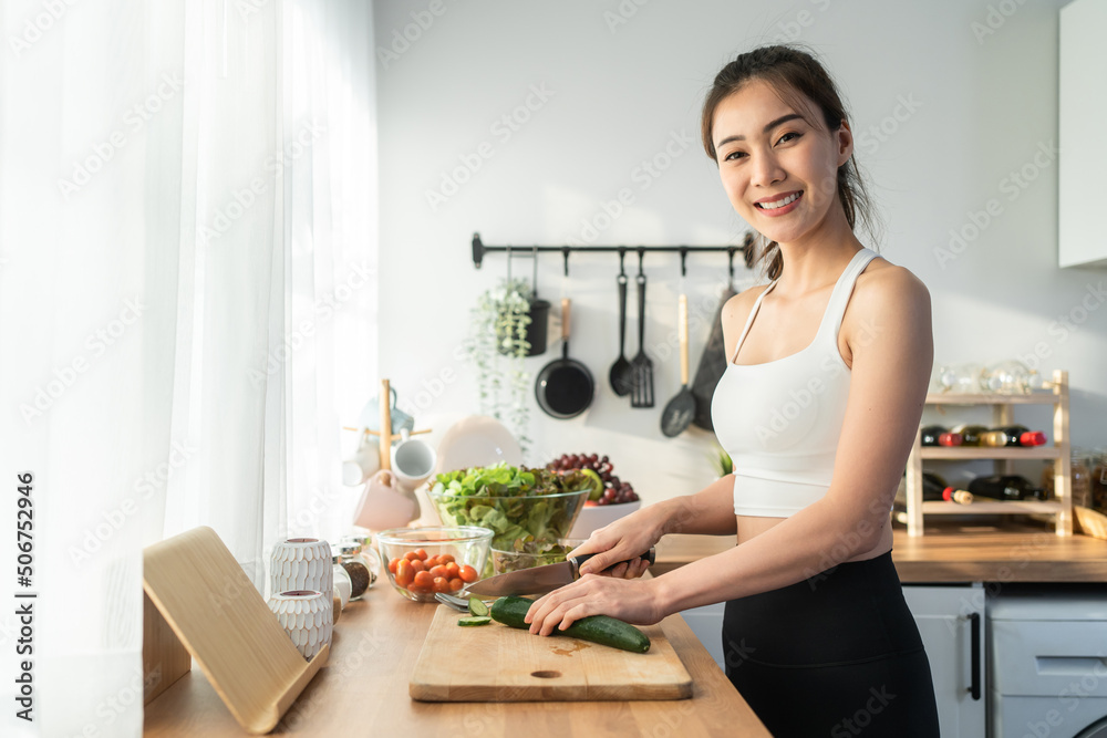 Portrait of Asian attractive woman cooking salad and looking at camera