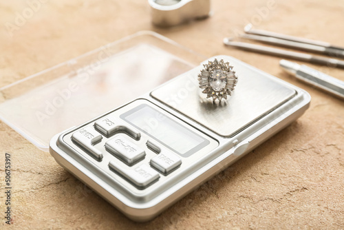 Jewelry scales with ring on beige background