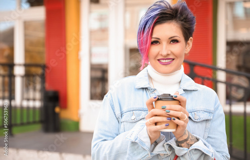 Beautiful woman with dyed hair and cup of coffee outdoors