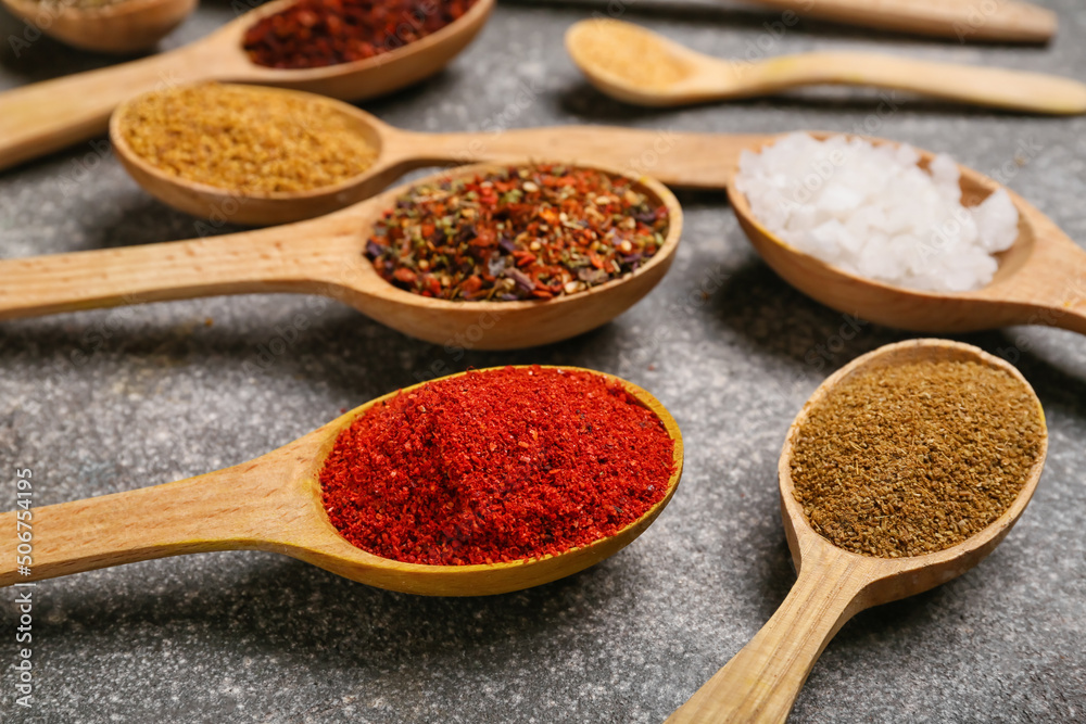 Spoons with aromatic spices on grey background, closeup Spoons with aromatic spices on grey background, closeup