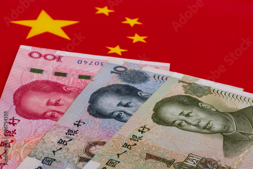 Banknotes in denominations of 1, 10 and 100 yuan against the background of the Chinese flag photo