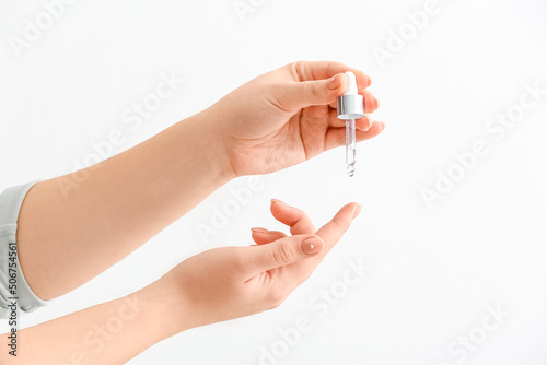 Woman applying serum onto hand on white background  closeup