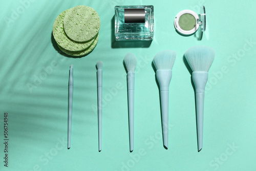 Makeup brushes with sponges  perfume and cosmetics on blue background